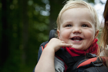 Baby boy riding in a carrier, piggyback with his mother, close-up - FSIF00751