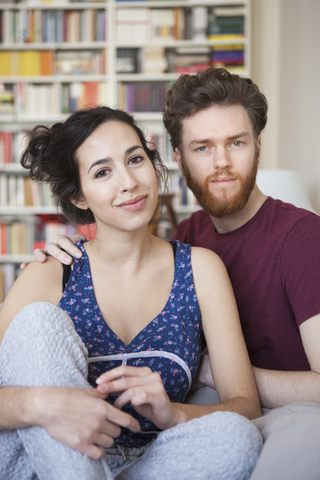 Porträt einer jungen Frau mit einem Mann, der sich zu Hause entspannt, lizenzfreies Stockfoto