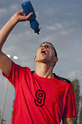 Young male soccer playing squirting water on face - FSIF00920
