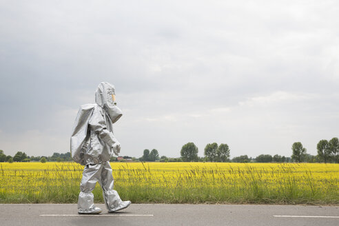 A person in a radiation protective suit walking alongside an oilseed rape field - FSIF00933