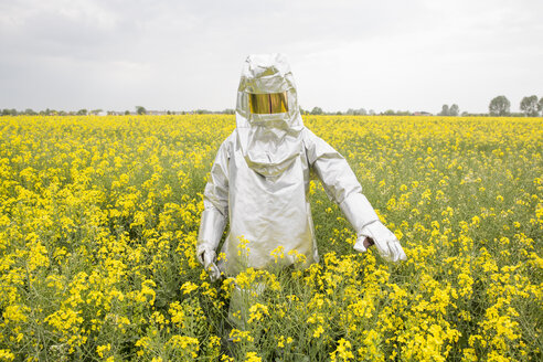 Eine Person in einem Strahlenschutzanzug steht in einem Rapsfeld - FSIF00934