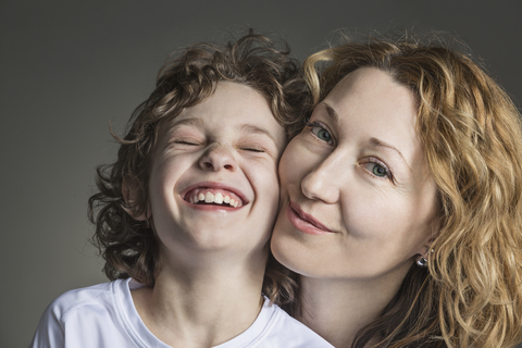 Nahaufnahme Porträt der Mutter mit fröhlichen Sohn über grauen Hintergrund, lizenzfreies Stockfoto