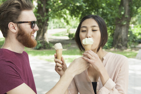 Glücklicher Mann füttert Frau im Park mit Eiscreme - FSIF00961