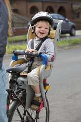 Porträt eines glücklichen Jungen auf dem Rücksitz eines Fahrrads - FSIF00979