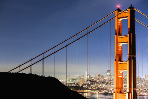 Golden Gate Bridge mit beleuchtetem Stadtbild im Hintergrund - FSIF00986