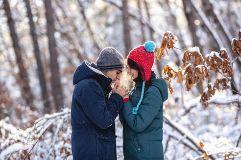 Seitenansicht eines romantischen jungen Paares, das sich im Winter an den Händen hält - FSIF00990