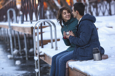 Glückliches junges Paar beim Kaffee trinken auf dem Pier sitzend - FSIF00992