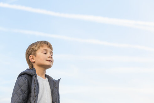 Low angle view of boy with eyes closed against sky - FSIF00994