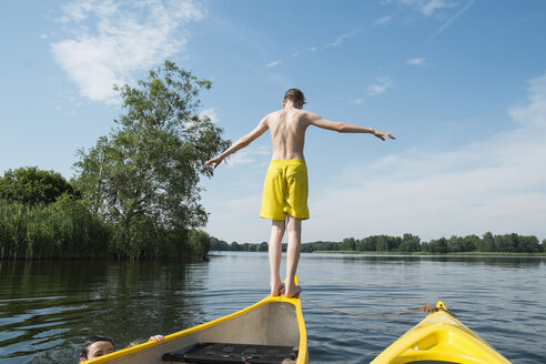 Rückansicht eines Jungen, der aus einem Kanu in einen See springt - FSIF00999