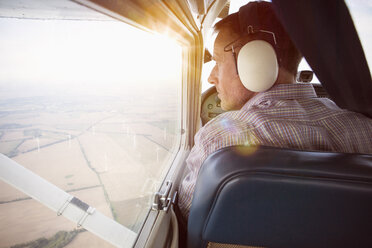 Rückansicht eines Mannes, der durch das Fenster eines Privatflugzeugs schaut - FSIF01003
