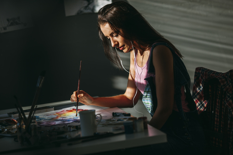 Weibliche Künstlerin malt am Tisch im Kunstatelier, lizenzfreies Stockfoto