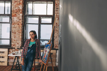 Porträt einer selbstbewussten Malerin vor einer Leinwand im Atelier - FSIF01013
