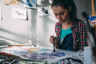 Female artist painting at table in art studio - FSIF01015