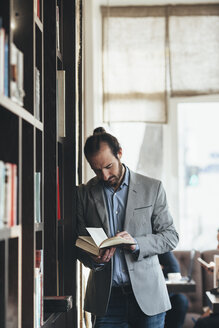 Mittlerer Erwachsener Geschäftsmann, der in einem Café ein Buch liest - FSIF01022