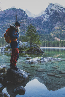 Seitenansicht einer Wanderin, die auf einem Felsen am Hintersee vor den Bergen steht - FSIF01023