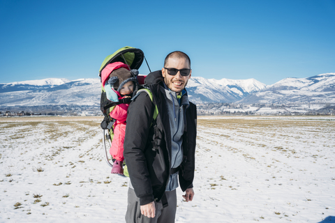 Spain, Puigcerda, father with baby girl in a kid carrier backpack during a hike at winter stock photo