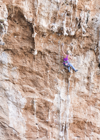 Greece, Kalymnos, woman climbing in rock wall stock photo