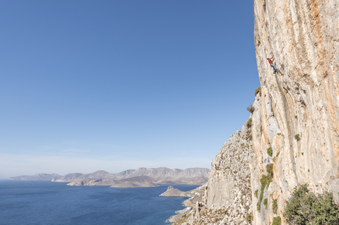 Griechenland, Kalymnos, Kletterer in Felswand über dem Meer, lizenzfreies Stockfoto