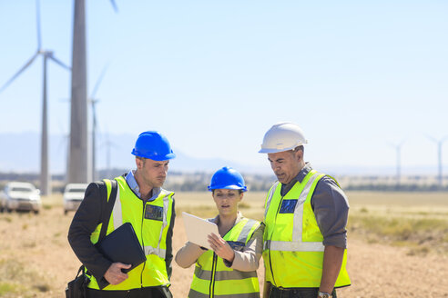 Drei Ingenieure mit Tablet, die in einem Windpark diskutieren - ZEF14954