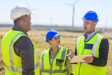 Drei Ingenieure mit Tablet, die in einem Windpark diskutieren - ZEF14955