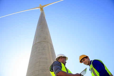 Low angle view of technicians with tablet in front of wind turbine stock photo