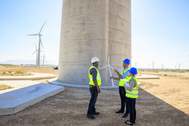 Drei Ingenieure mit einem Windturbinenmodell bei der Diskussion in einem Windpark - ZEF14967
