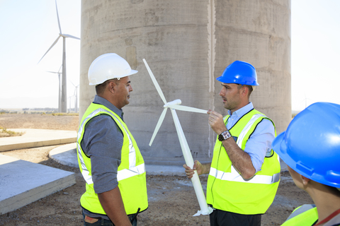 Three engineers with wind turbine model discussing on a wind farm stock photo