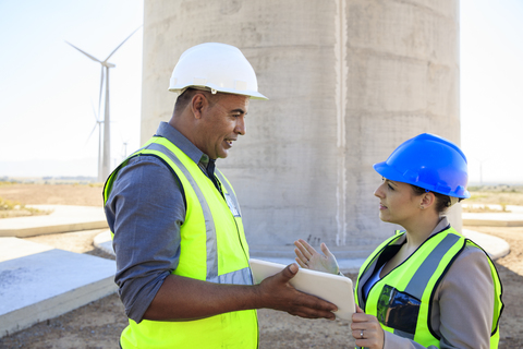 Two engineers with tablet discussing on a wind farm stock photo