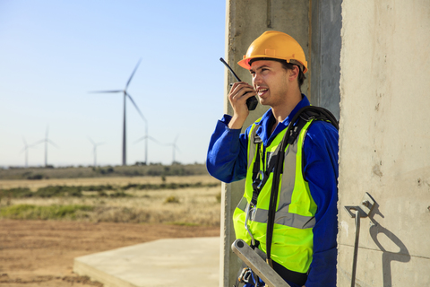 Technician using walkie-talkie at wind turbine stock photo