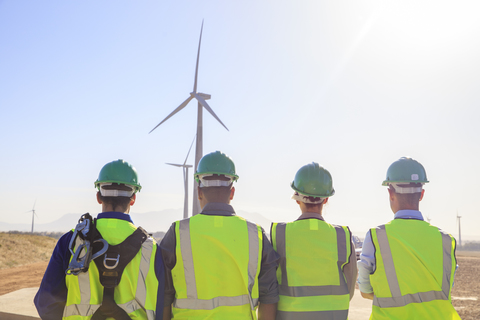 Rückansicht von vier Ingenieuren in einem Windpark, lizenzfreies Stockfoto