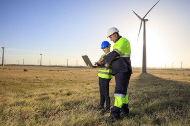 Zwei Ingenieure mit Laptop, die in einem Windpark diskutieren - ZEF14980