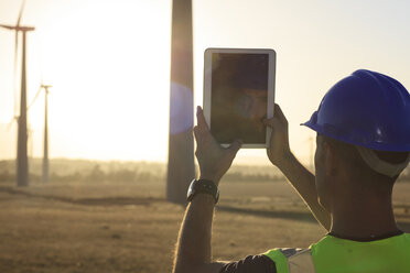 Ingenieur fotografiert mit einem Tablet einen Windpark bei Sonnenuntergang - ZEF14986