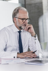 Älterer Geschäftsmann arbeitet am Schreibtisch im Büro - UUF12726