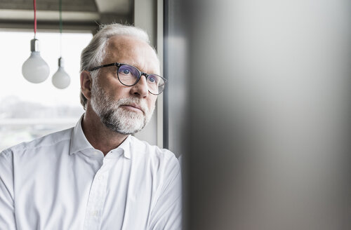 Seriöser reifer Geschäftsmann schaut aus dem Fenster - UUF12746