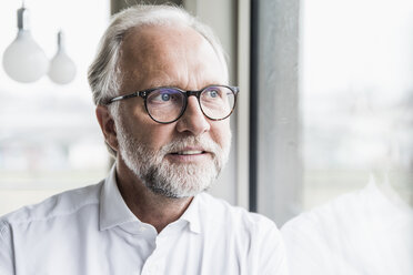 Porträt eines reifen Geschäftsmannes, der aus dem Fenster schaut - UUF12747