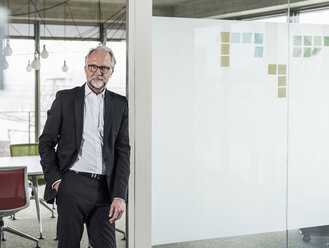 Porträt eines selbstbewussten reifen Geschäftsmannes, der im Büro steht - UUF12757