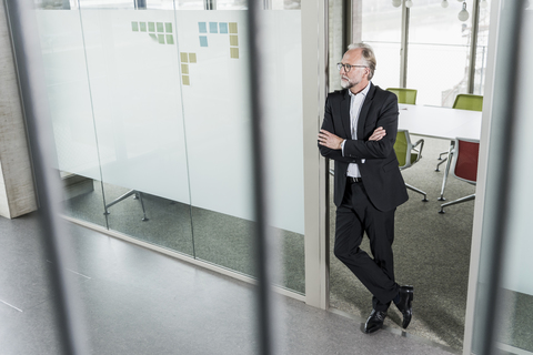 Mature businessman standing in office thinking stock photo