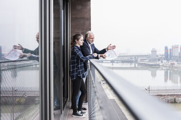 Älterer Geschäftsmann und junge Frau unterhalten sich auf dem Balkon - UUF12790