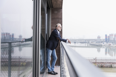 Älterer Geschäftsmann auf Balkon stehend, lizenzfreies Stockfoto