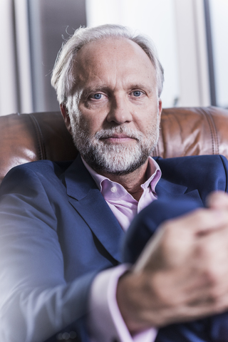 Portrait of mature businessman sitting in leather armchair stock photo