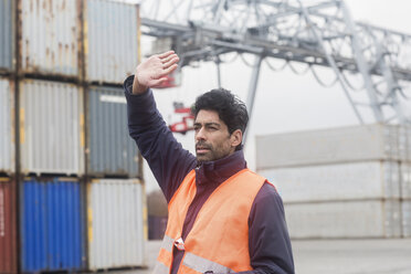 Mann mit Warnweste bei der Arbeit im Containerhafen - SGF02183