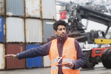 Mann mit Tablet und Warnweste im Containerhafen - SGF02184