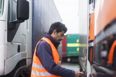 Mann mit Warnweste bei der Untersuchung eines Lastwagens - SGF02186