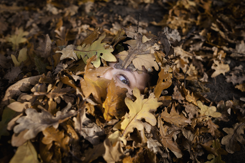 Nahaufnahme einer mit trockenen Blättern bedeckten Frau im Herbst, lizenzfreies Stockfoto