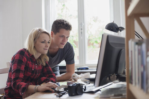 Junges Paar, das zu Hause einen Computer am Fenster benutzt - FSIF01080