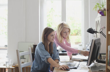 Blonde Frau zeigt auf Computermonitor zu Freundin - FSIF01082