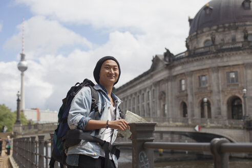 Lächelnder junger männlicher Tourist, der mit einer Karte am Geländer des Bode-Museums steht, Berlin, Deutschland - FSIF01089