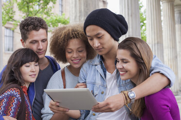 Junger Mann zeigt multiethnischen Freunden ein digitales Tablet - FSIF01099