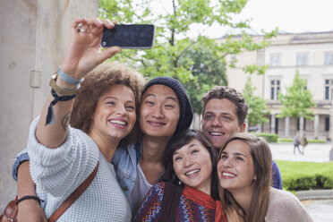 Lächelnde junge Frau macht Selfie mit multiethnischen Freunden, Berlin, Deutschland - FSIF01101