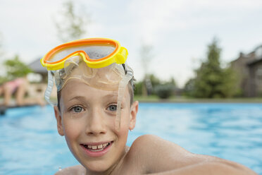 Porträt eines lächelnden Jungen ohne Hemd mit Schwimmbrille im Pool - FSIF01112